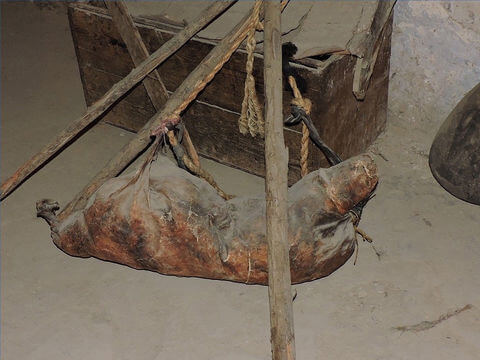 Replica of an ancient wineskin hanging on wooden poles.