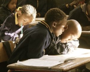 Schoolchildren doing their lessons on wooden desks.