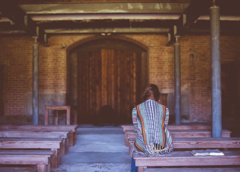 Woman sitting alone in empty church, wanting to please God