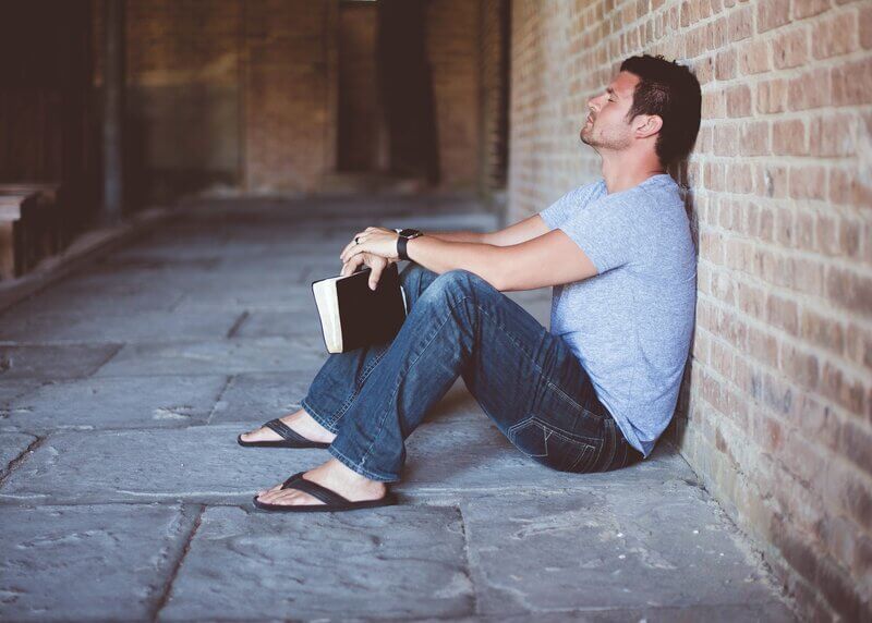 Young man with Bible praying to become more like Christ.
