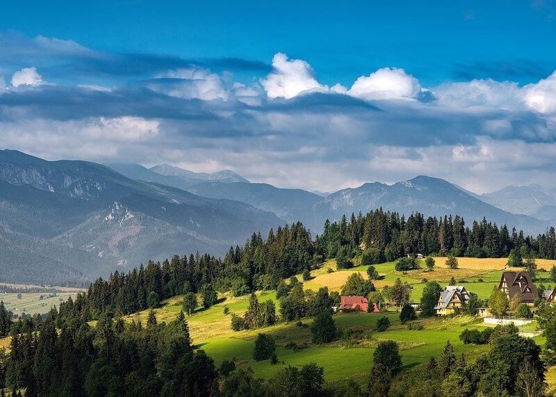 God's goodness as shown in photo of green hillside with houses and mountains in background