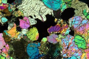 Beautiful colors from light passing through a thin section of spinel lherzolite rock under plane polarized light