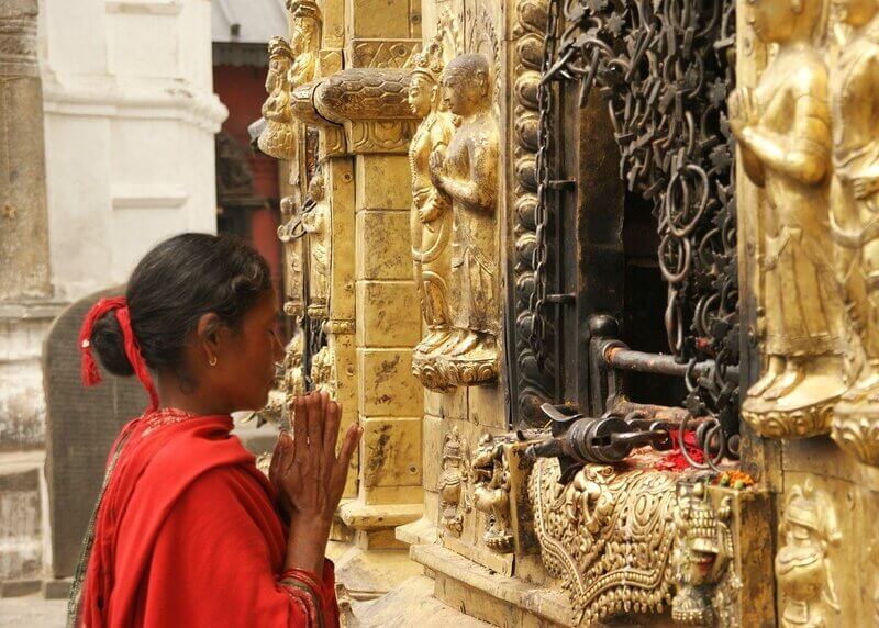 Woman praying and giving an offering before a shrine practicing a ritualistic religion