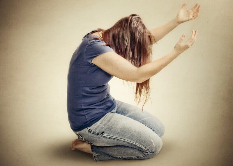 Woman kneeling and lifting hands up before God, giving herself as a living sacrifice to God